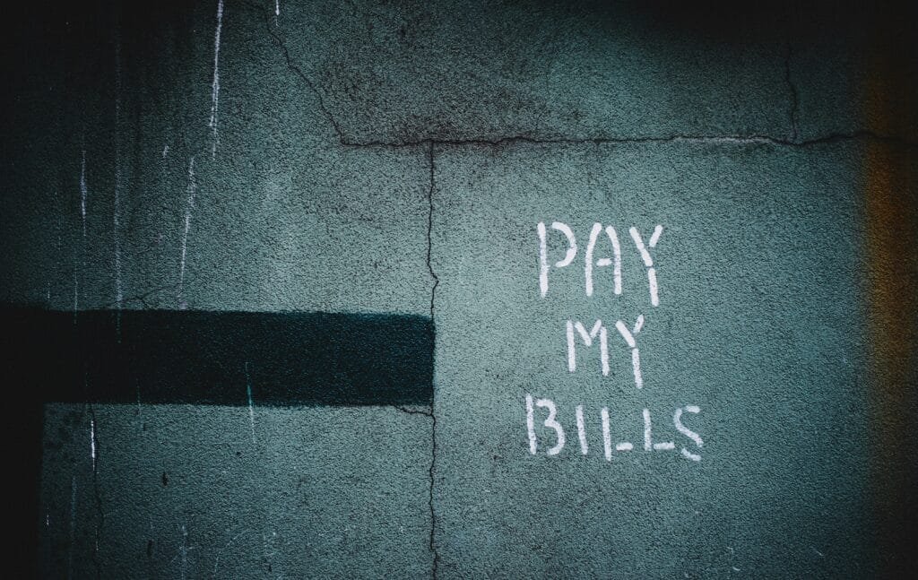 Handwritten “Pay My Bills” on a wall, symbolizing overdue invoices and illustrating How to Handle Late Payments for freelancers and small businesses.